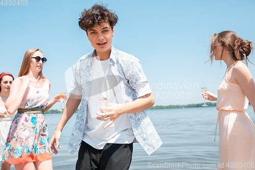 Image of Seasonal feast at beach resort. Group of friends celebrating, resting, having fun on the beach in sunny summer day