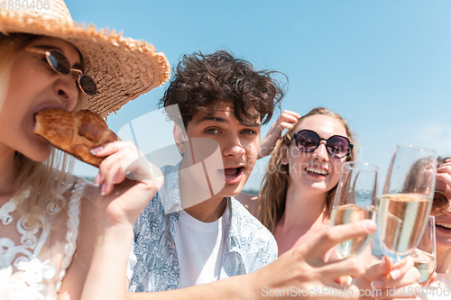 Image of Seasonal feast at beach resort. Group of friends celebrating, resting, having fun on the beach in sunny summer day