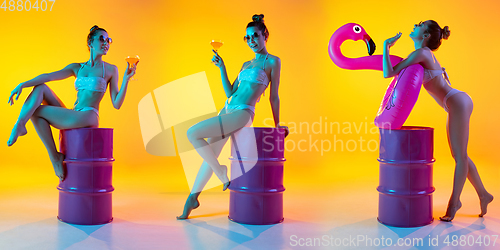 Image of Fashion portrait of seductive girl in stylish swimwear posing on a bright yellow background. Summertime, beach season