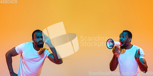 Image of African man\'s portrait isolated on yellow studio background in neon light