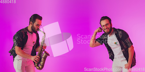 Image of Young caucasian jazz musician playing the saxophone in neon light, flyer