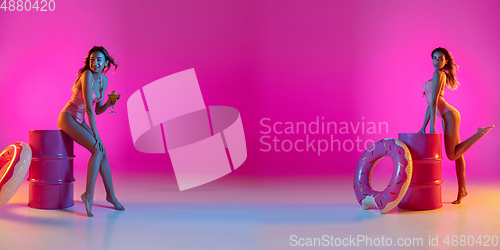 Image of Fashion portrait of seductive girl in stylish swimwear posing on a bright pink background. Summertime, beach season