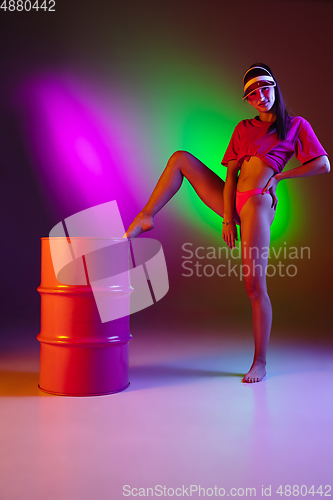 Image of Beautiful seductive girl in fashionable swimsuit on disco bicolored neon studio background in neon light. Summer, resort, fashion and weekend concept