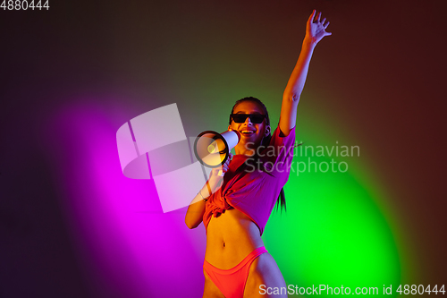 Image of Beautiful seductive girl in fashionable swimsuit on disco bicolored neon studio background in neon light. Summer, resort, fashion and weekend concept