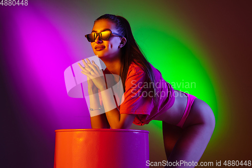 Image of Beautiful seductive girl in fashionable swimsuit on disco bicolored neon studio background in neon light. Summer, resort, fashion and weekend concept