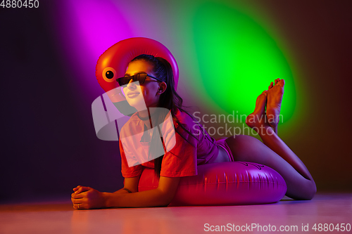 Image of Beautiful seductive girl in fashionable swimsuit on disco bicolored neon studio background in neon light. Summer, resort, fashion and weekend concept