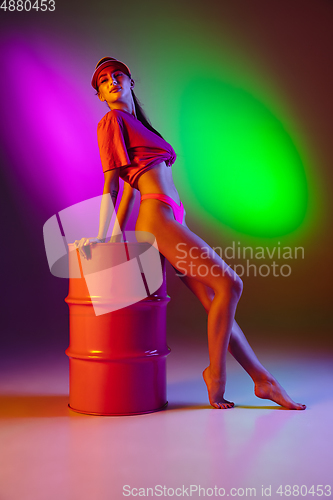 Image of Beautiful seductive girl in fashionable swimsuit on disco bicolored neon studio background in neon light. Summer, resort, fashion and weekend concept