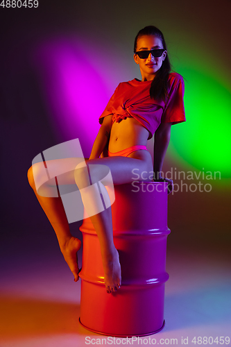 Image of Beautiful seductive girl in fashionable swimsuit on disco bicolored neon studio background in neon light. Summer, resort, fashion and weekend concept