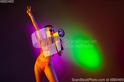 Image of Beautiful seductive girl in fashionable swimsuit on disco bicolored neon studio background in neon light. Summer, resort, fashion and weekend concept