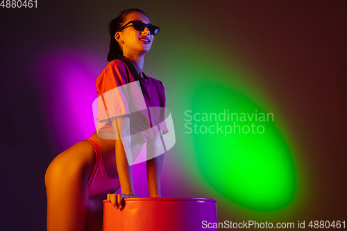 Image of Beautiful seductive girl in fashionable swimsuit on disco bicolored neon studio background in neon light. Summer, resort, fashion and weekend concept