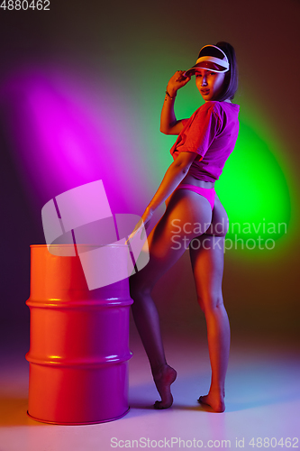 Image of Beautiful seductive girl in fashionable swimsuit on disco bicolored neon studio background in neon light. Summer, resort, fashion and weekend concept