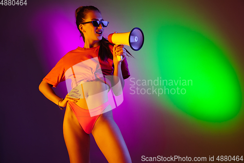 Image of Beautiful seductive girl in fashionable swimsuit on disco bicolored neon studio background in neon light. Summer, resort, fashion and weekend concept