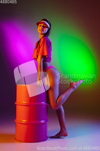 Image of Beautiful seductive girl in fashionable swimsuit on disco bicolored neon studio background in neon light. Summer, resort, fashion and weekend concept