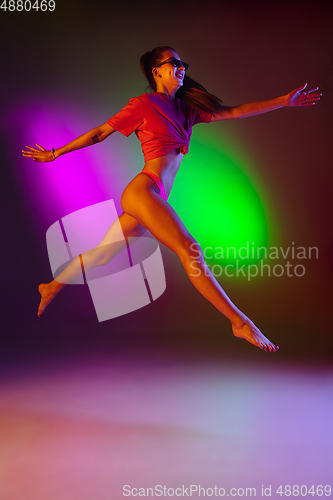 Image of Beautiful seductive girl in fashionable swimsuit on disco bicolored neon studio background in neon light. Summer, resort, fashion and weekend concept