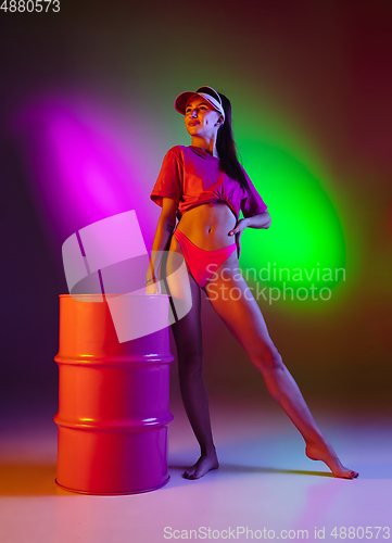 Image of Beautiful seductive girl in fashionable swimsuit on disco bicolored neon studio background in neon light. Summer, resort, fashion and weekend concept