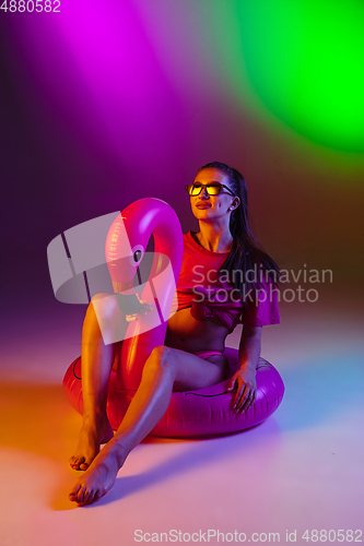 Image of Beautiful seductive girl in fashionable swimsuit on disco bicolored neon studio background in neon light. Summer, resort, fashion and weekend concept
