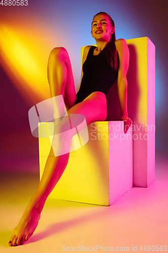 Image of Beautiful seductive girl in fashionable swimsuit on disco bicolored neon studio background in neon light. Summer, resort, fashion and weekend concept