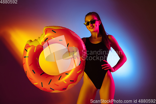 Image of Beautiful seductive girl in fashionable swimsuit on disco bicolored neon studio background in neon light. Summer, resort, fashion and weekend concept