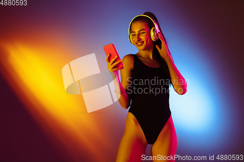 Image of Beautiful seductive girl in fashionable swimsuit on disco bicolored neon studio background in neon light. Summer, resort, fashion and weekend concept