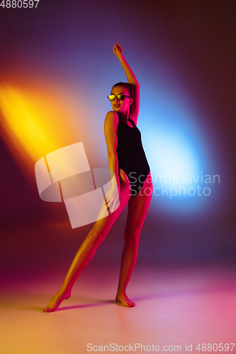 Image of Beautiful seductive girl in fashionable swimsuit on disco bicolored neon studio background in neon light. Summer, resort, fashion and weekend concept