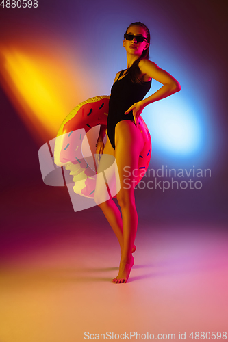 Image of Beautiful seductive girl in fashionable swimsuit on disco bicolored neon studio background in neon light. Summer, resort, fashion and weekend concept