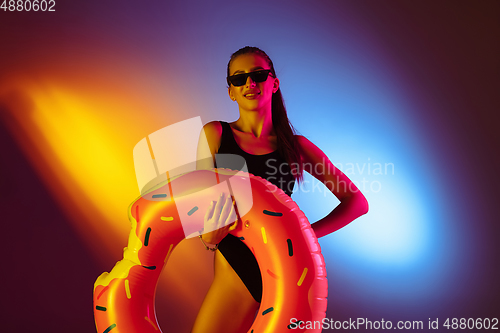 Image of Beautiful seductive girl in fashionable swimsuit on disco bicolored neon studio background in neon light. Summer, resort, fashion and weekend concept