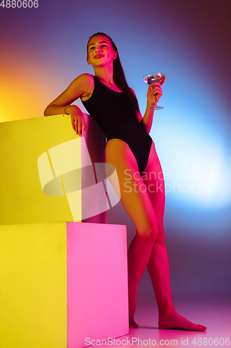 Image of Beautiful seductive girl in fashionable swimsuit on disco bicolored neon studio background in neon light. Summer, resort, fashion and weekend concept