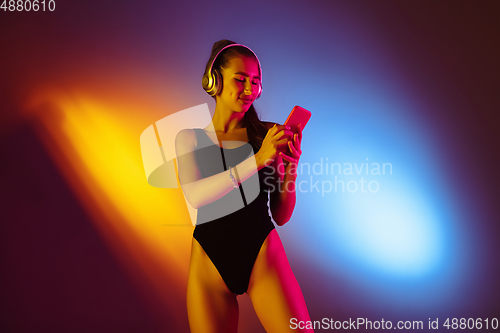 Image of Beautiful seductive girl in fashionable swimsuit on disco bicolored neon studio background in neon light. Summer, resort, fashion and weekend concept