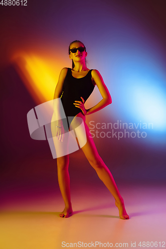 Image of Beautiful seductive girl in fashionable swimsuit on disco bicolored neon studio background in neon light. Summer, resort, fashion and weekend concept