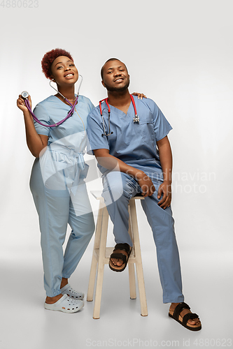 Image of Couple of beautiful african-american doctors or nurses smiling isolated over white studio background