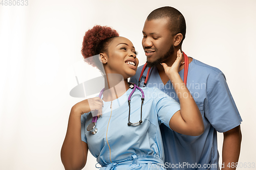 Image of Couple of beautiful african-american doctors or nurses smiling isolated over white studio background