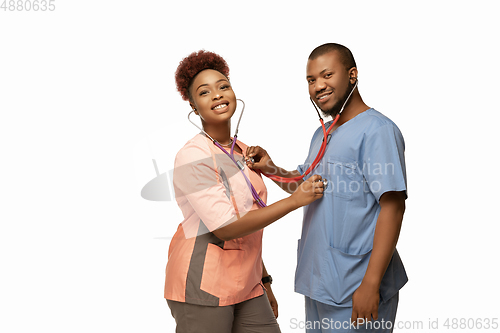 Image of Couple of beautiful african-american doctors or nurses smiling isolated over white studio background