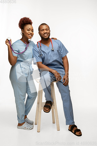 Image of Couple of beautiful african-american doctors or nurses smiling isolated over white studio background