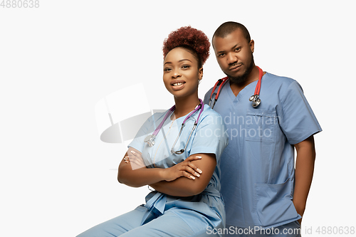 Image of Couple of beautiful african-american doctors or nurses smiling isolated over white studio background