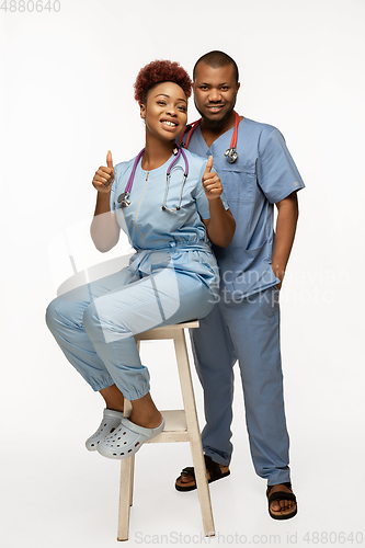 Image of Couple of beautiful african-american doctors or nurses smiling isolated over white studio background