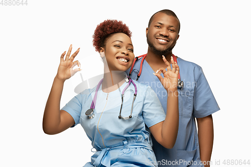 Image of Couple of beautiful african-american doctors or nurses smiling isolated over white studio background