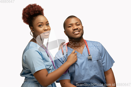Image of Couple of beautiful african-american doctors or nurses smiling isolated over white studio background