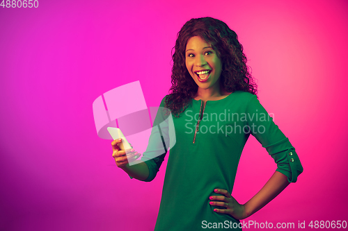 Image of African-american young woman\'s portrait isolated on gradient pink background in neon light