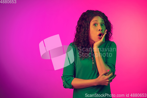 Image of African-american young woman\'s portrait isolated on gradient pink background in neon light