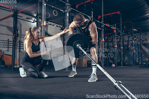 Image of Beautiful young sporty couple training, workout in gym together