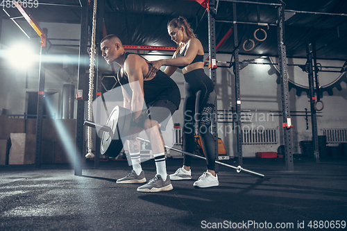 Image of Beautiful young sporty couple training, workout in gym together