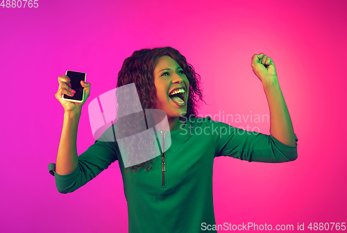 Image of African-american young woman\'s portrait isolated on gradient pink background in neon light