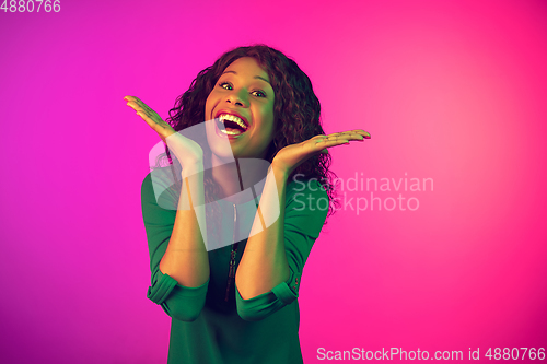 Image of African-american young woman\'s portrait isolated on gradient pink background in neon light