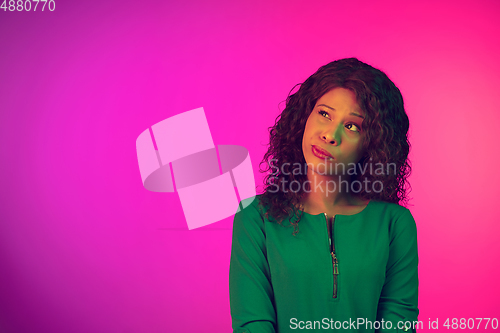 Image of African-american young woman\'s portrait isolated on gradient pink background in neon light