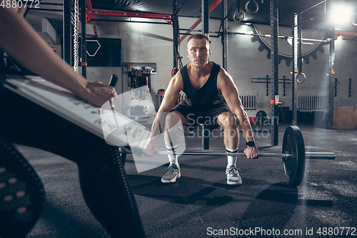 Image of Beautiful young sporty couple training, workout in gym together