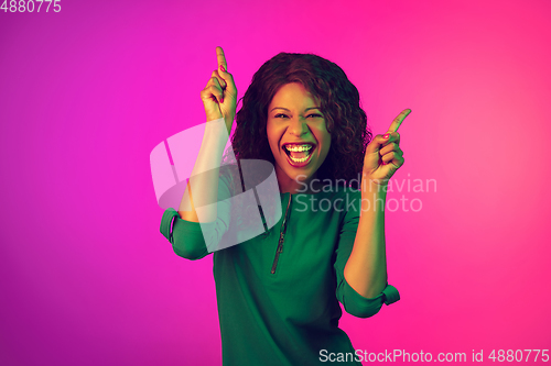 Image of African-american young woman\'s portrait isolated on gradient pink background in neon light