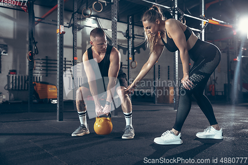 Image of Beautiful young sporty couple training, workout in gym together