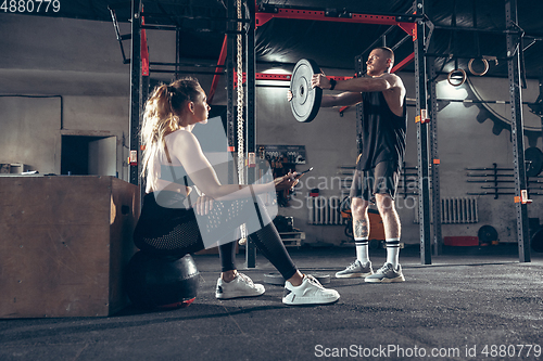 Image of Beautiful young sporty couple training, workout in gym together