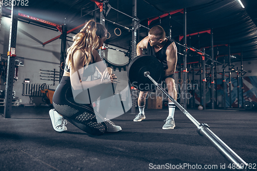 Image of Beautiful young sporty couple training, workout in gym together