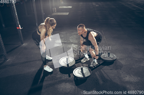 Image of Beautiful young sporty couple training, workout in gym together